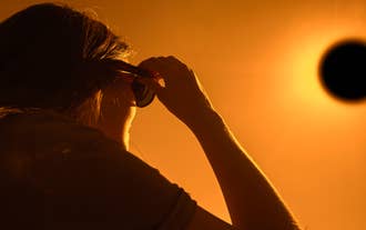 Et bilde av en kvinne som ser mot solen på en solformørkelsestur.
