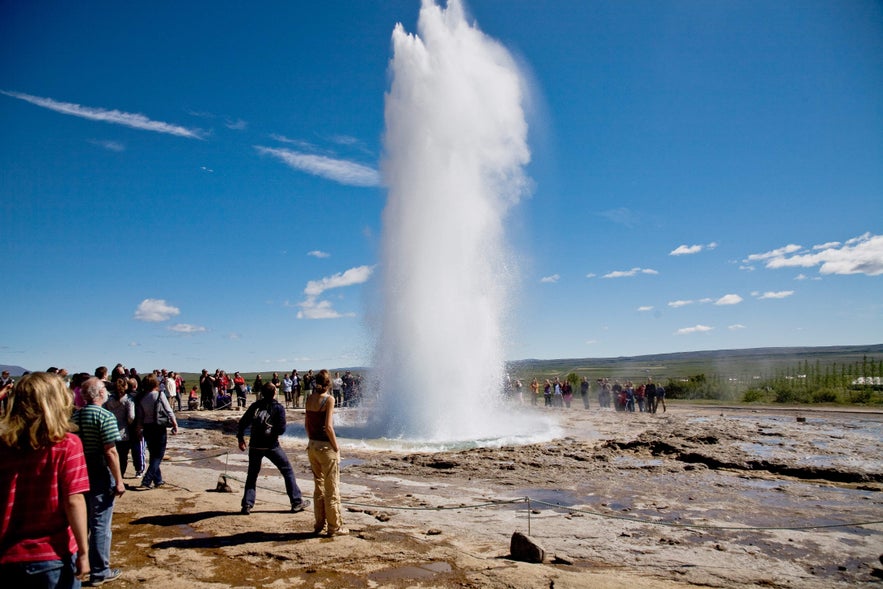 En gruppe mennesker samlet sig omkring Strokkur i det geotermiske omr&aring;de Geysir, som er en del af Den Gyldne Cirkel-rute i Island.