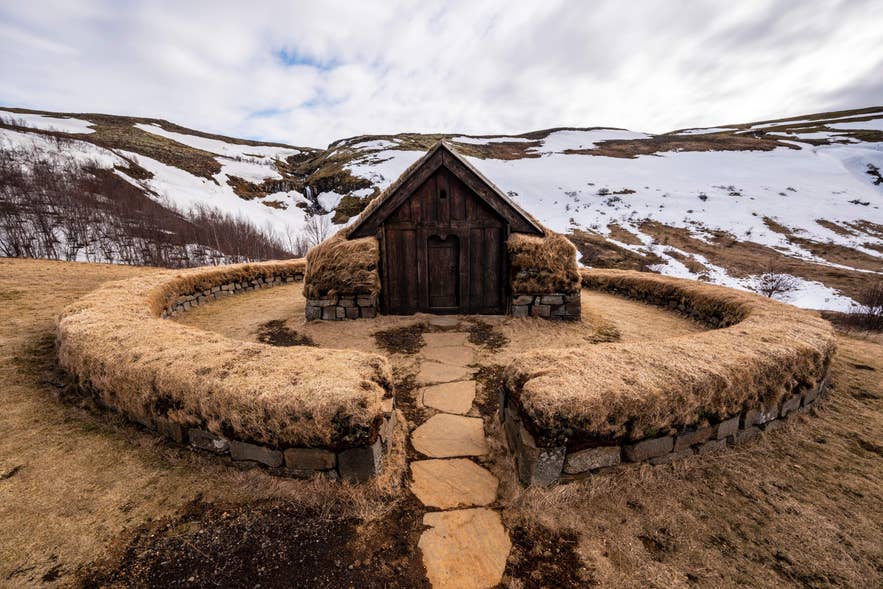 A rustic wooden house stands alone in a field, located in the tranquil Thjorsardalur Valley, ideal for nature lovers.