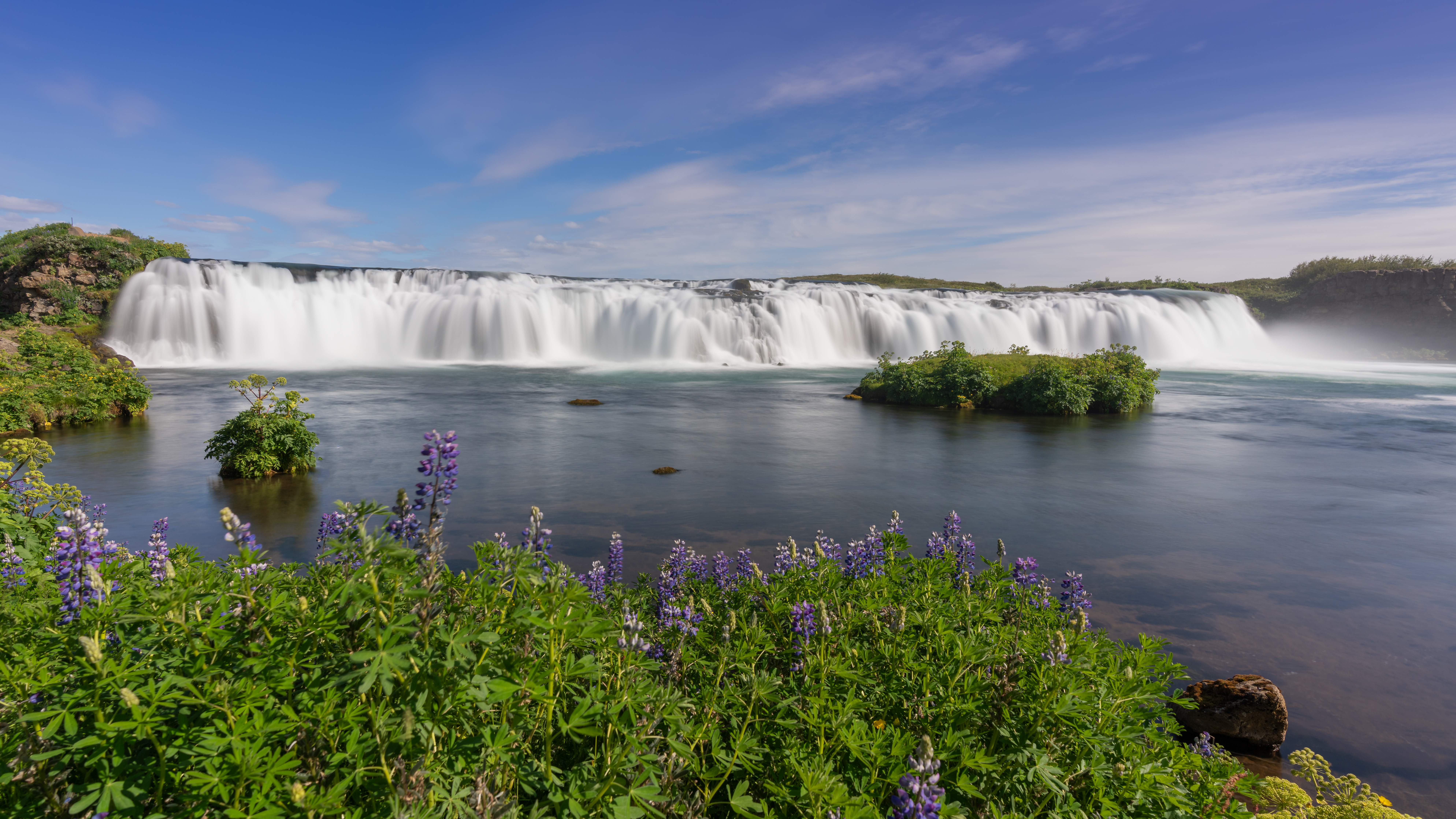 Scenic view of Faxafoss Waterfall in Iceland, a calm cascade along the Tungufljot River, framed by verdant surroundings.