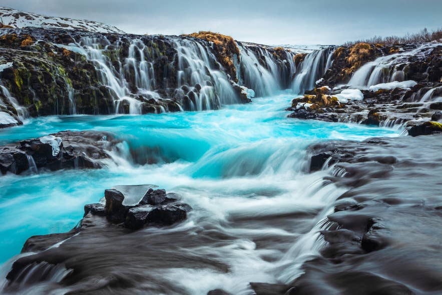 La cascade de Bruarfoss dévoile de magnifiques eaux turquoise qui s'écoulent sur des formations rocheuses uniques, un lieu idéal pour les amoureux de la nature et les photographes.