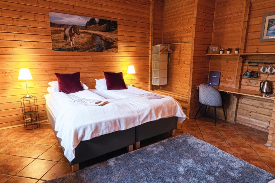 Przytulna sypialnia z drewnianymi ścianami i łóżkiem, oferująca rustykalny wypoczynek w Efstidalur Farm Hotel na islandzkiej wsi.