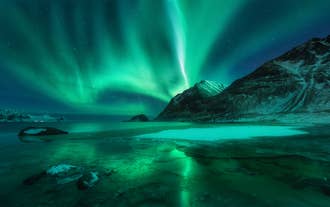 Auroras boreales danzando sobre un paisaje helado y una laguna congelada en Islandia bajo un cielo nocturno despejado.