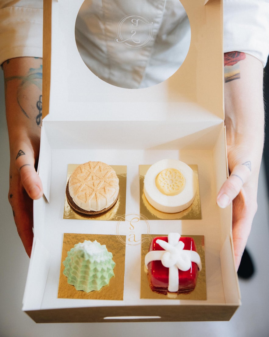 Box of four artistic pastries from Sweet Aurora, each uniquely shaped and colorfully designed.