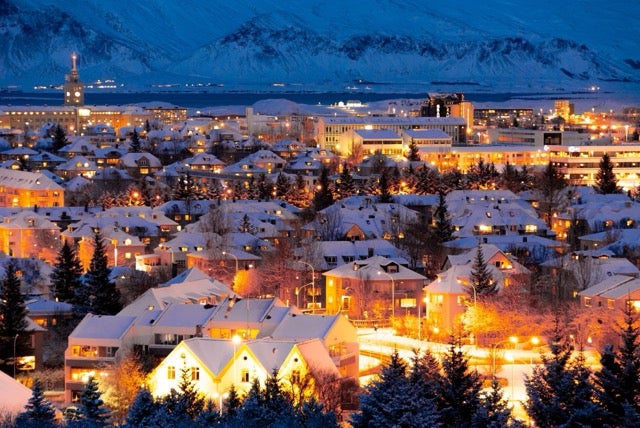 Houses in Reykjavik are covered in snow and glow with warm lights one winter day. 