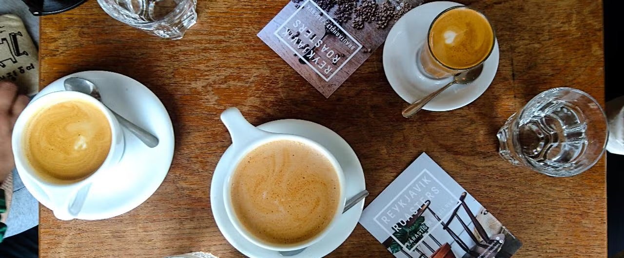 Overhead view of three coffees on the table with Reykjavik Roasters posters.