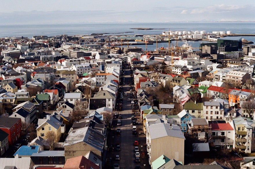 Aerial view of downtown Reykjavik in April with colorful houses, harbor, and ocean in the distance.