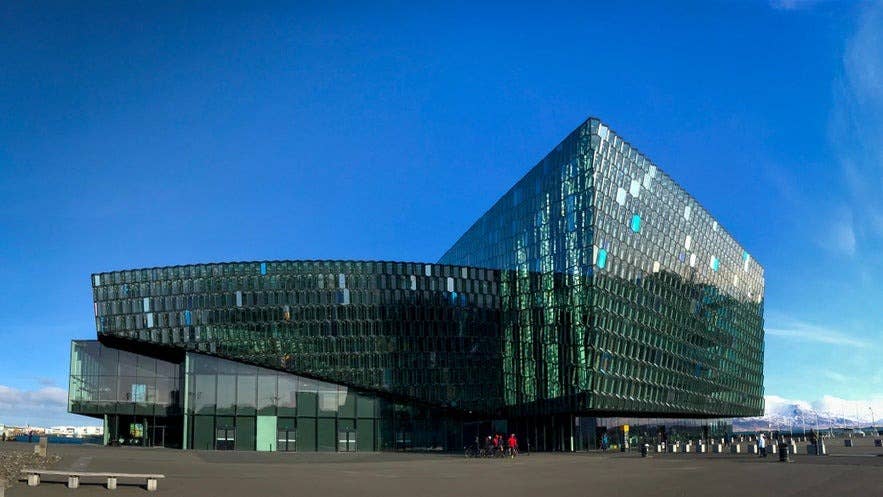Harpa Concert Hall in Reykjavik in April with glass windows reflecting the harbor and sky.