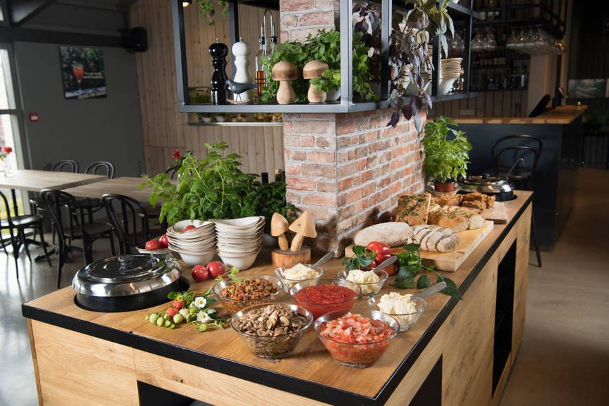 Table de buffet au Fludasveppir Farmers Bistro, présentant un assortiment de plats et de boissons pour les clients.