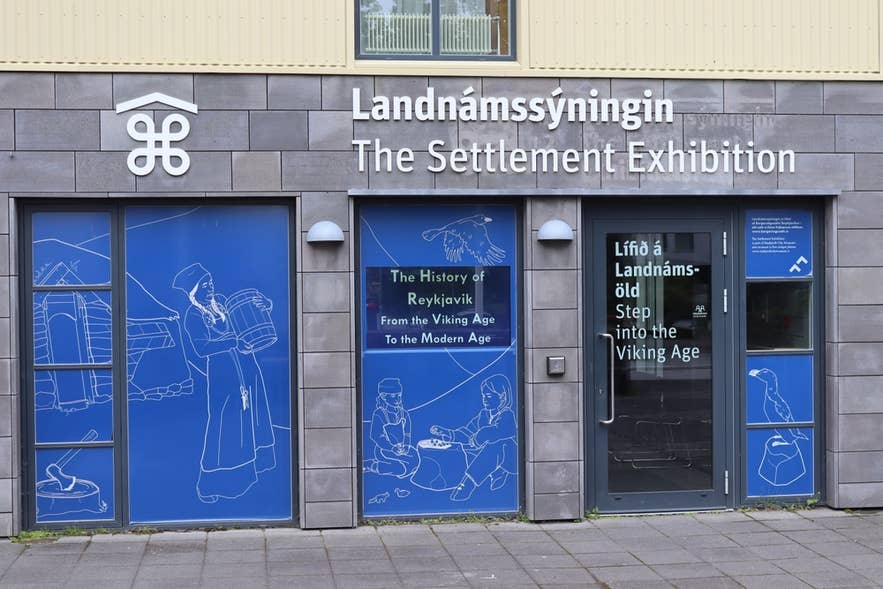 Entrance to the Settlement Exhibition in Reykjavik in April showing blue Viking-themed artwork and museum signs.