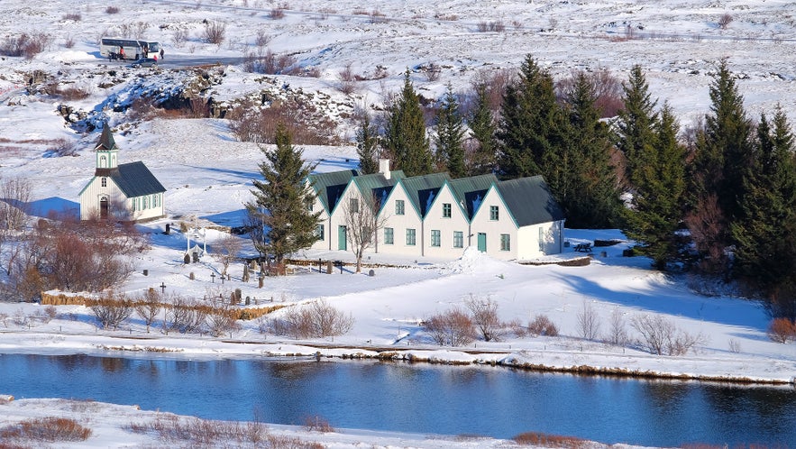 La chiesa di Thingvallakirkja situata su un pendio innevato accanto a un fiume, immersa nella bellezza invernale di Thingvellir, in Islanda.