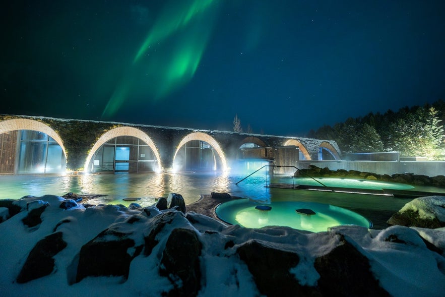 Det geotermiske spa Laugar&aacute;s Lagoon p&aring; Island med nordlys, der lyser over de varme pools p&aring; en vinternat
