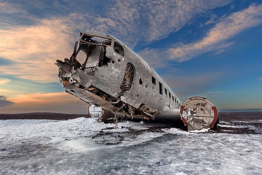 ソゥルへイマサンドゥルの黒い砂浜に残る米海軍DC-3機の残骸。雪とカラフルな空に囲まれている。