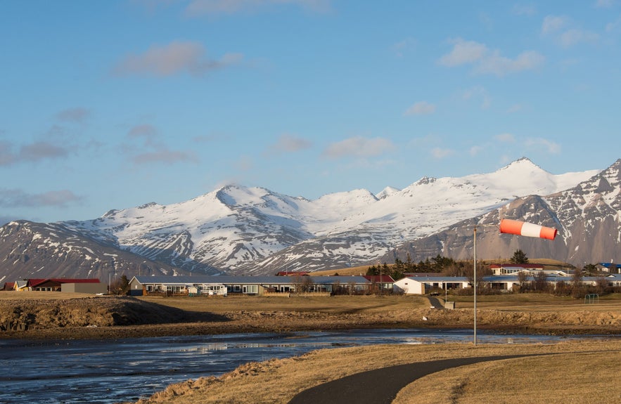 Вид на город Хёбн на юго-востоке Исландии, на фоне заснеженных гор и ветроуказателя у аэропорта