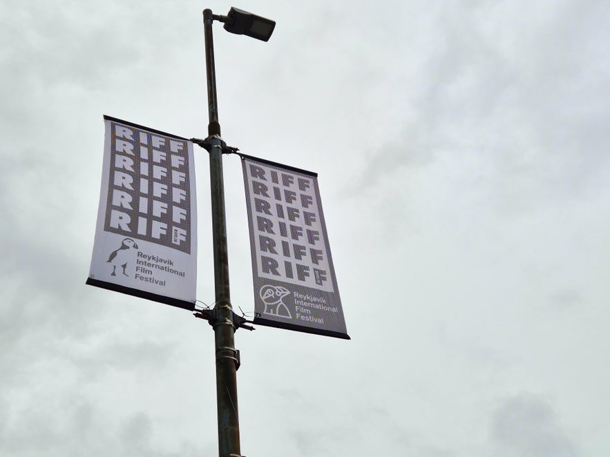 Street banners for the Reykjavik International Film Festival (RIFF) hanging from a lamp post under a cloudy sky.