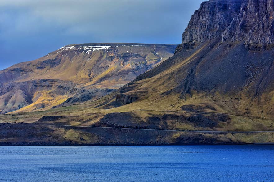 Route 47 running along the shore of Hvalfjordur beneath a snow-streaked ridge in West Iceland. Route 47 running along the shore of Hvalfjordur beneath a snow-streaked ridge in West Iceland.