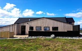 Wooden Lonkot guesthouse in Iceland with black roofing set against a clear blue sky.