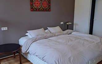 A bright bedroom in Lonkot featuring a large bed, soft bedding, and colorful wall art.