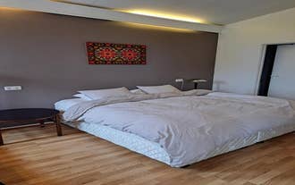 A bright bedroom in Lonkot featuring a large bed, soft bedding, and colorful wall art.