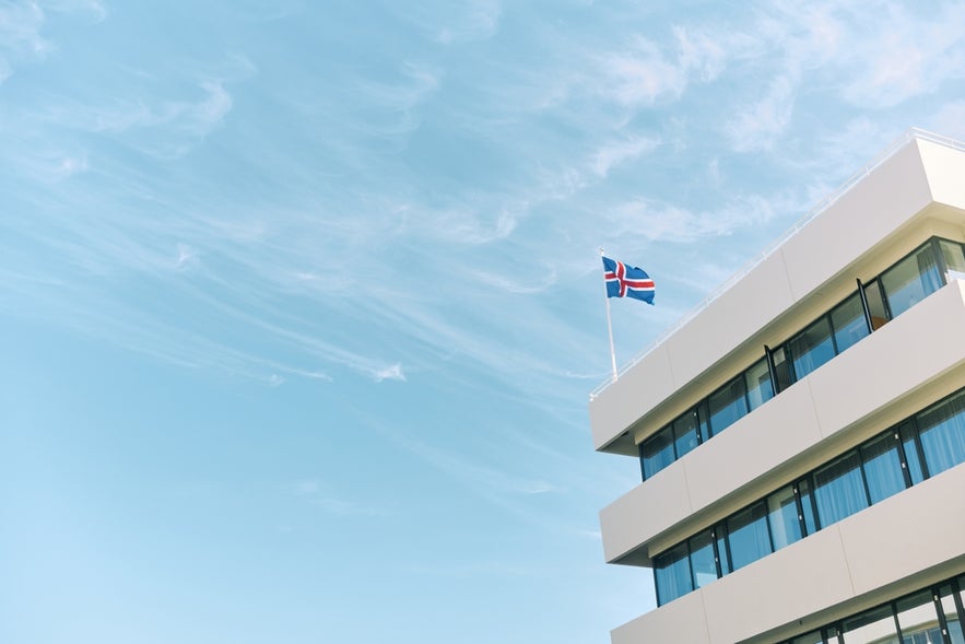 Icelandic flag flying on a modern building, providing career opportunities and work in Iceland.
