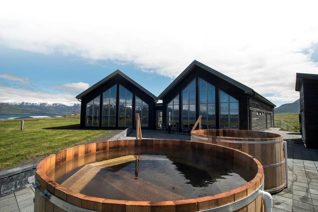 Bains chauds extérieurs du Beer Spa Bjorbodin en Islande face aux montagnes et au fjord.