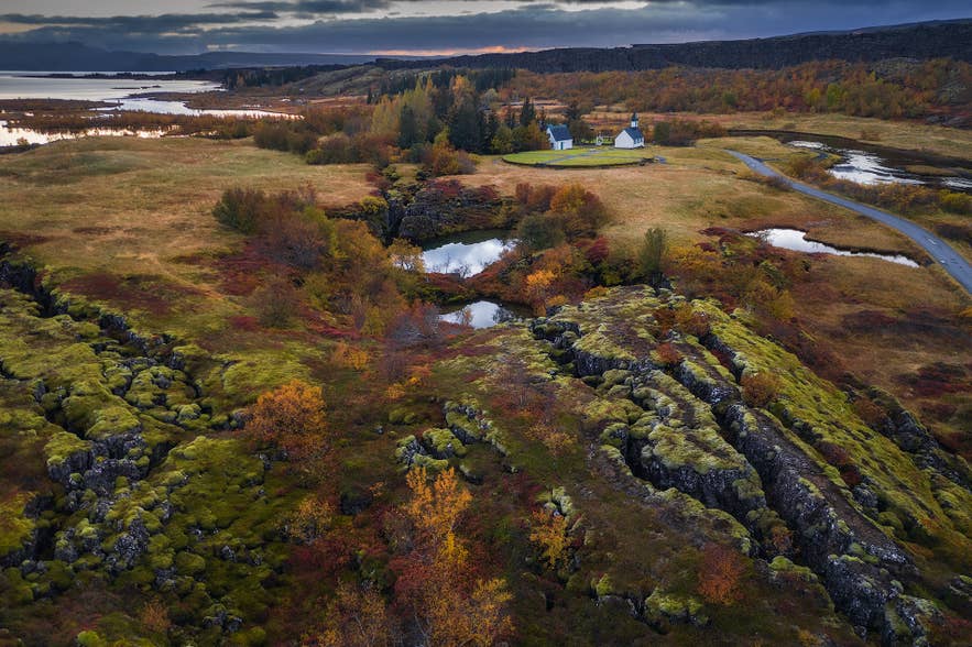 Vue automnale du parc national de Thingvellir en Islande, avec sa vallée de faille recouverte de mousse, ses étangs et l'historique église de Thingvallakirkja.