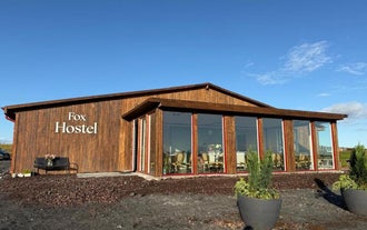 Modern wooden exterior of Fox Hostel in South Iceland with large glass windows.