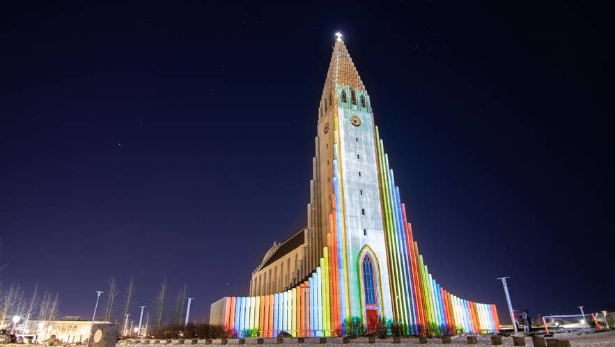 Hallgrimskirkja church lit with colorful beams during Reykjavik Winter Lights Festival in Iceland at night.
