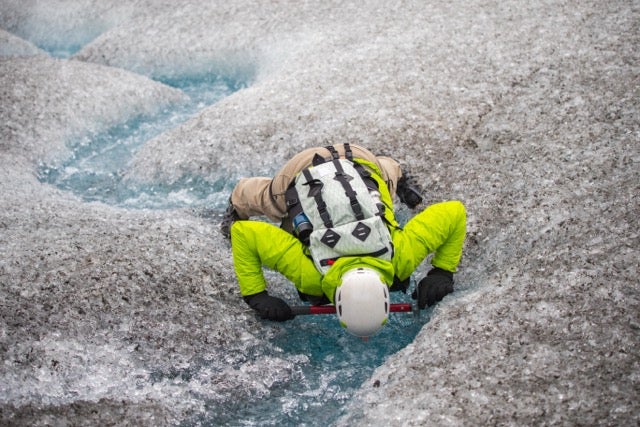 A hiker stoops down to drink glacier meltwater in Solheimajokul in the South Coast.