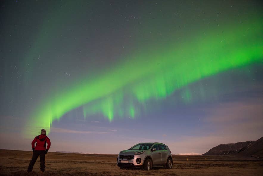 Visitor on a winter self-drive tour watching the northern lights in Iceland.