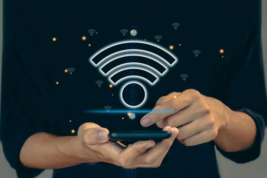 A man holds a mobile phone with a Wi-Fi logo that implies connectivity at Keflavik International Airport in Iceland.