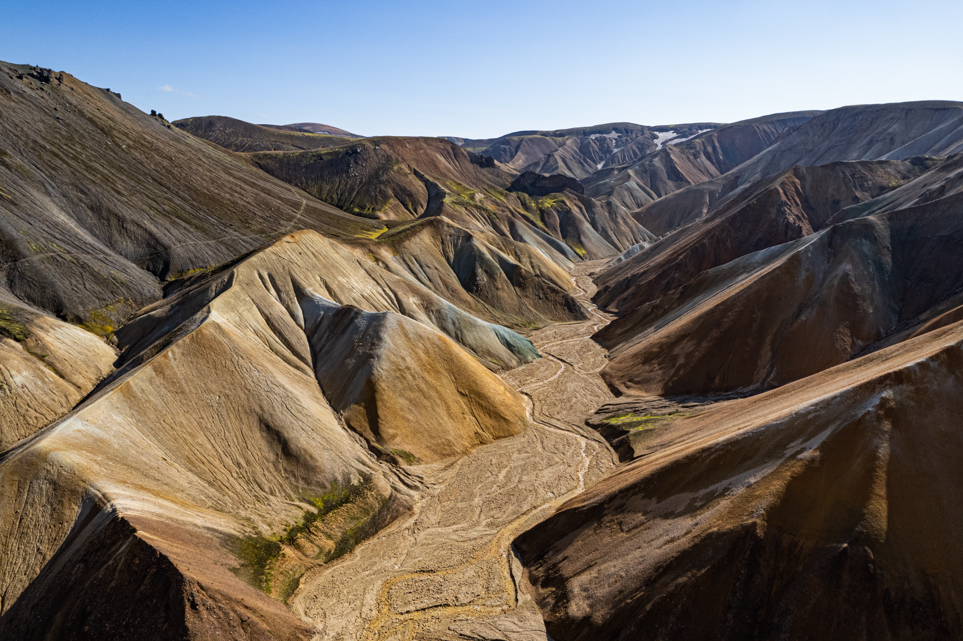 Rhyolite mountains and winding valleys in the Landmannalaugar highlands under clear daylight.