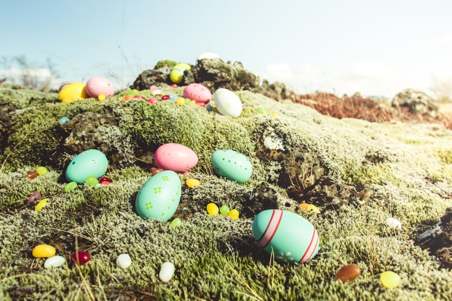 Colorful Easter eggs scattered on mossy lava rocks, showing Easter traditions in Iceland in April.