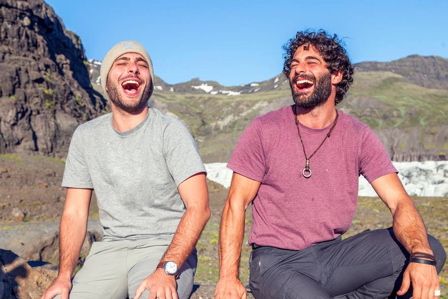 Due amici che ridono all’aperto in Islanda ad aprile, perfetto esempio dello spirito giocoso del Pesce d’aprile.