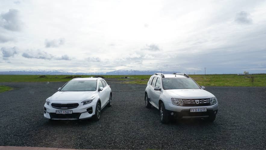 Rental cars parked on gravel with South Iceland mountains in the background, ideal for car rental in Iceland.