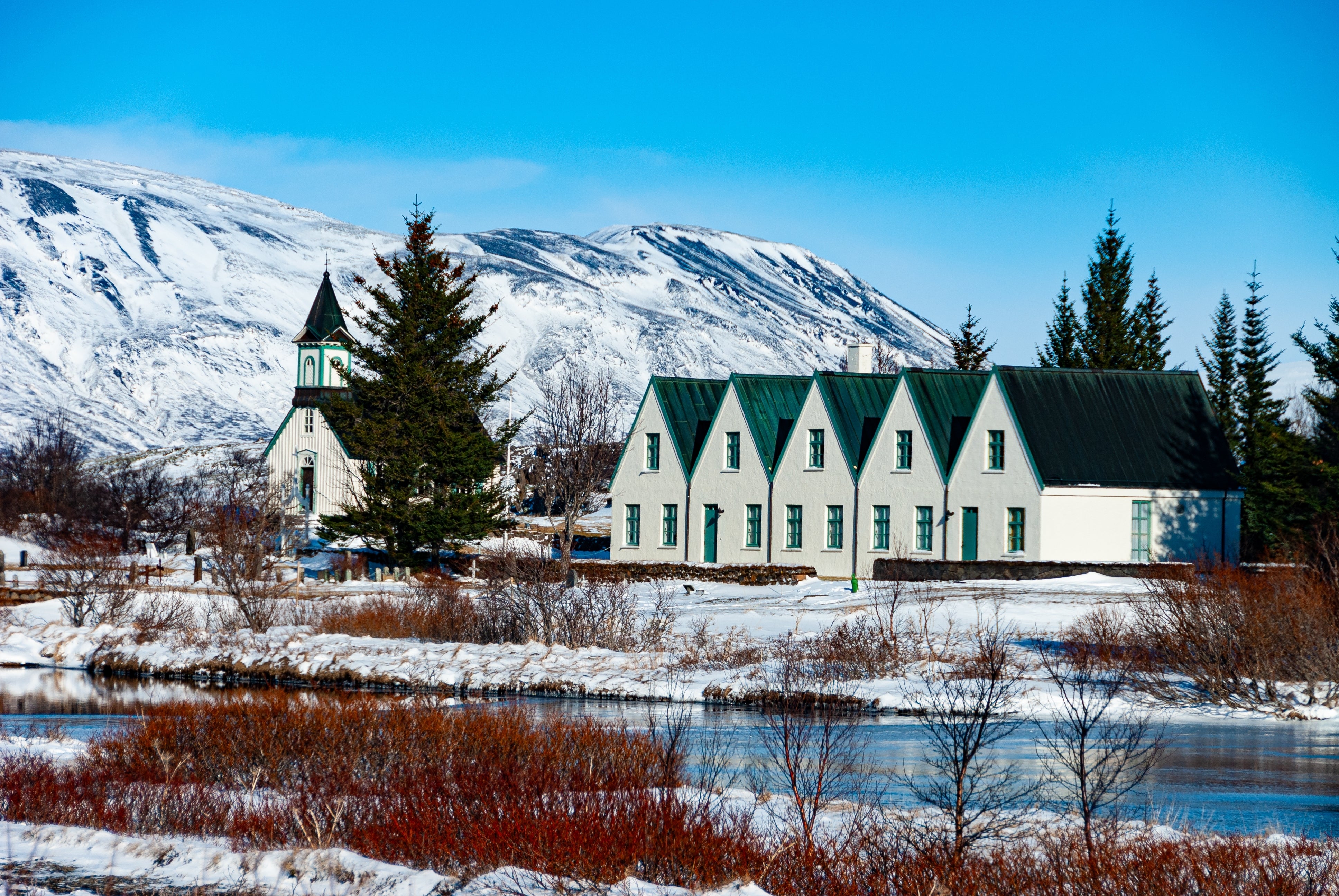 Thingvellir National Park with traditional buildings and snowy mountains.