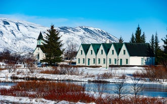 Thingvellir National Park with traditional buildings and snowy mountains.