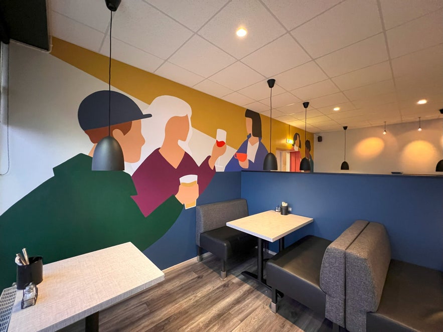 Cozy interior of Salt Café & Bistro in Iceland with modern booths, warm lighting, and colorful mural artwork.