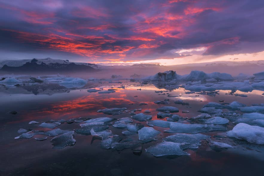 La lagune glaciaire de Jokulsarlon avec des blocs de glace flottants sous un ciel éclatant au coucher du soleil.