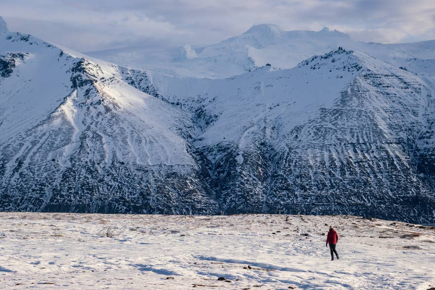 南アイスランド・スカフタフェットルで、スカフタフェルスヨークトル氷河の急斜面の下、雪原を歩くハイカー。