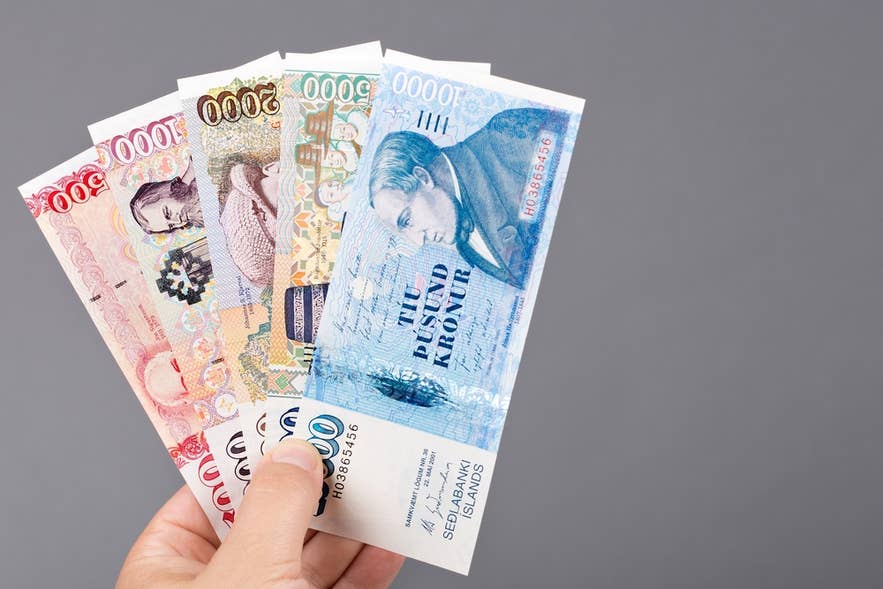 Eine Hand hält isländische Kronen-Banknoten und zeigt verschiedene Stückelungen der Währung in Island.