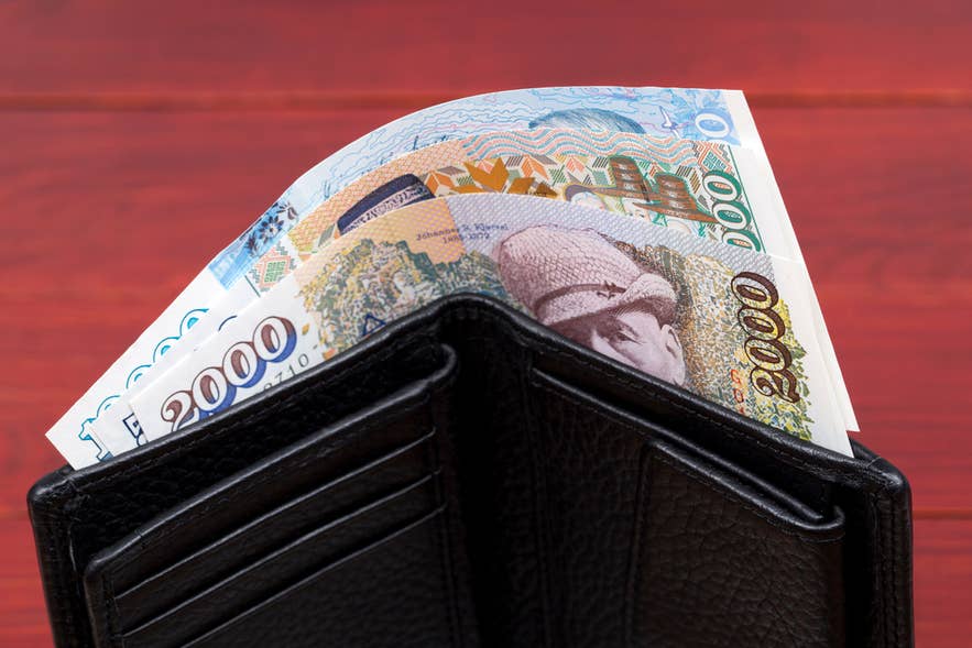 Isländische Kronen-Banknoten im Portemonnaie – so führen Reisende Bargeld in Island mit sich.