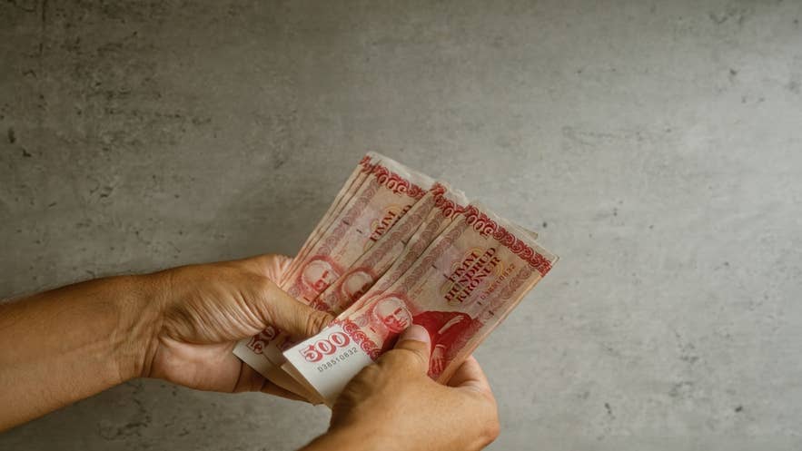 Eine Person hält isländische Kronen-Banknoten in der Hand – so sieht der Alltag mit Bargeld in Island aus.
