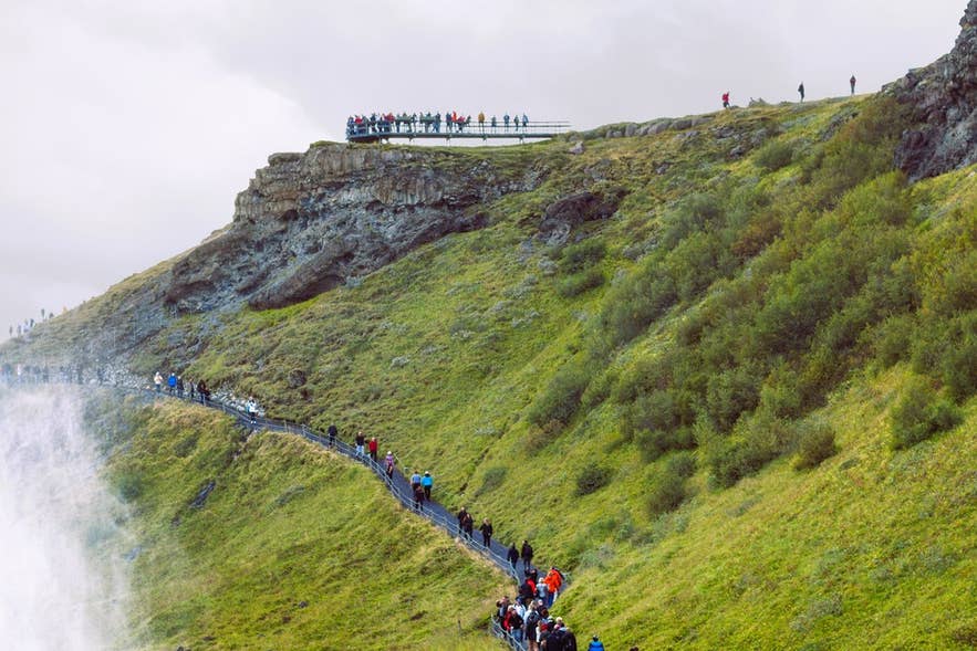 Visitantes caminando por el sendero y las plataformas sobre la cascada Gullfoss en el Círculo Dorado de Islandia.