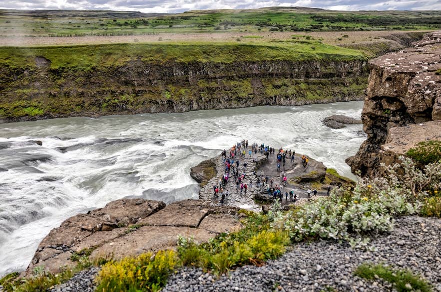 Toeristen op het lagere uitkijkplatform bij de Gullfoss-waterval aan de Golden Circle in IJsland. Toeristen op het lagere uitkijkplatform bij de Gullfoss-waterval aan de Golden Circle in IJsland.