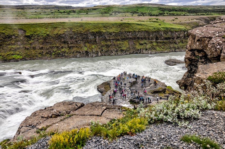 Touristen auf der unteren Aussichtsplattform am Gullfoss-Wasserfall am Goldenen Kreis Islands.