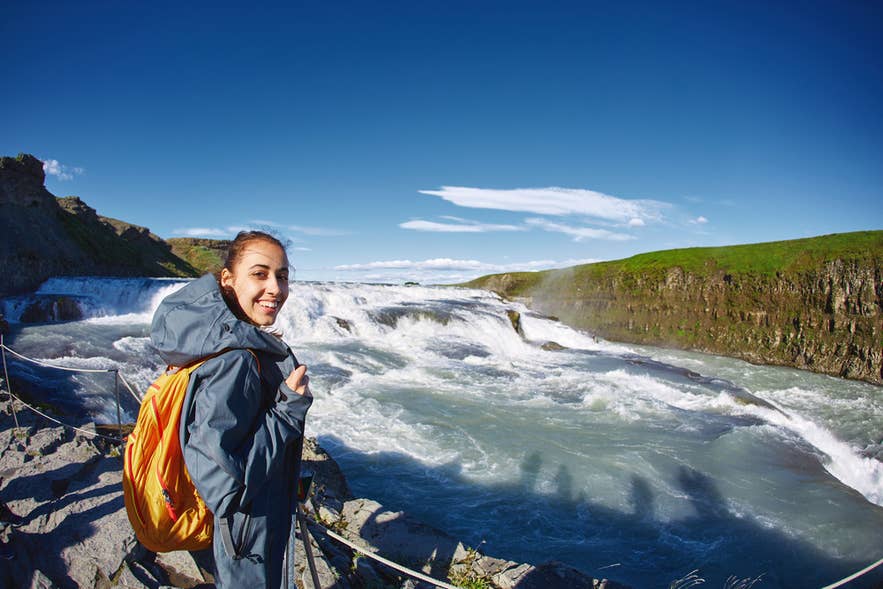 Wandelaar bij een uitkijkpunt naast de Gullfoss-waterval aan de Golden Circle in IJsland op een heldere zomerdag. Wandelaar bij een uitkijkpunt naast de Gullfoss-waterval aan de Golden Circle in IJsland op een heldere zomerdag.