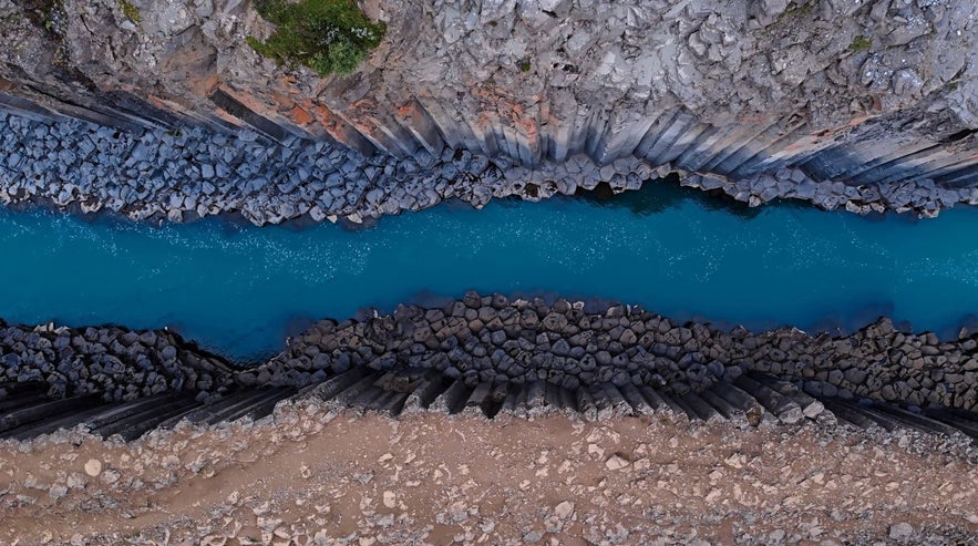 View of Studlagil canyon from the top looking down at the blue water in Iceland