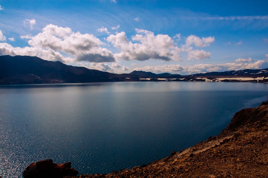 The best places to visit in East Iceland include Lake Lagarfljot with calm waters, snowy hills, and scenic skies.