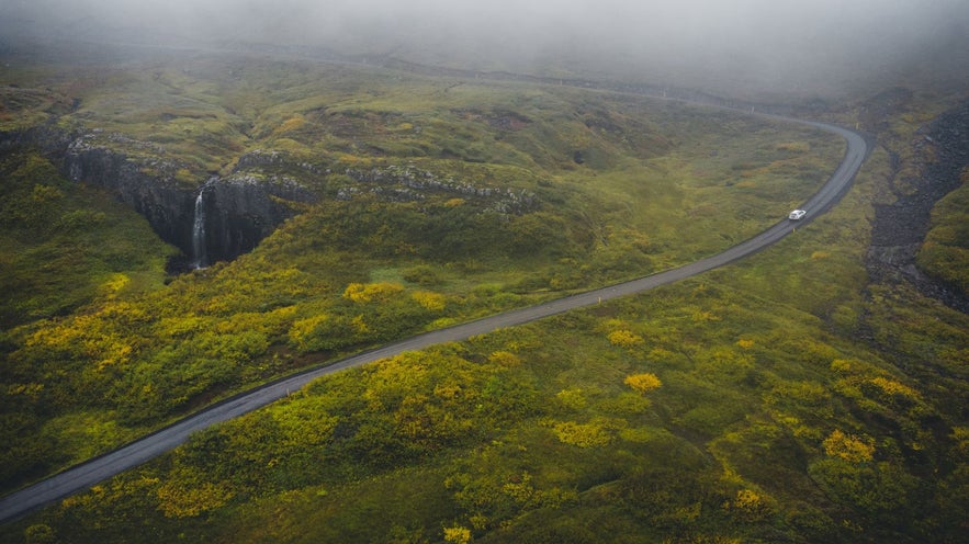 Car driving up a mossy mountain in the eastfjords of Iceland in summer